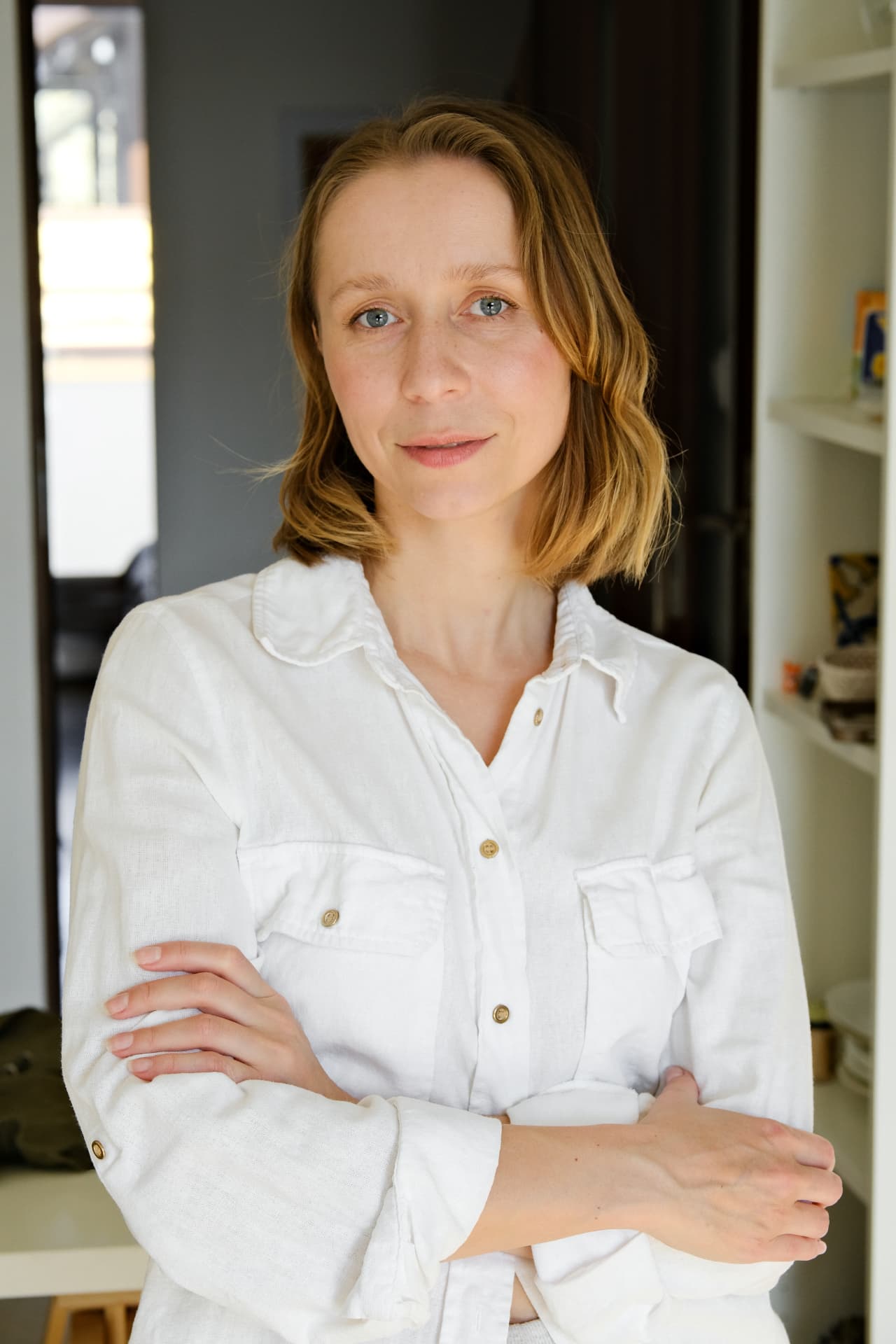 Woman with shoulder-length hair in a white shirt, arms crossed